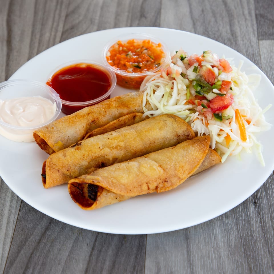 Crispy rolled tacos served with shredded cabbage, pico de gallo, and cups of creamy, red, and orange sauces.