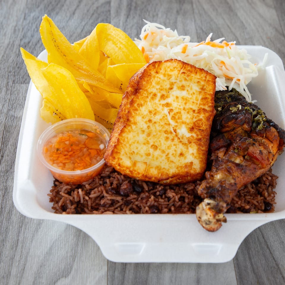 Takeout platter with grilled chicken, fried cheese, rice and beans, fried plantains, coleslaw, and orange dipping sauce.